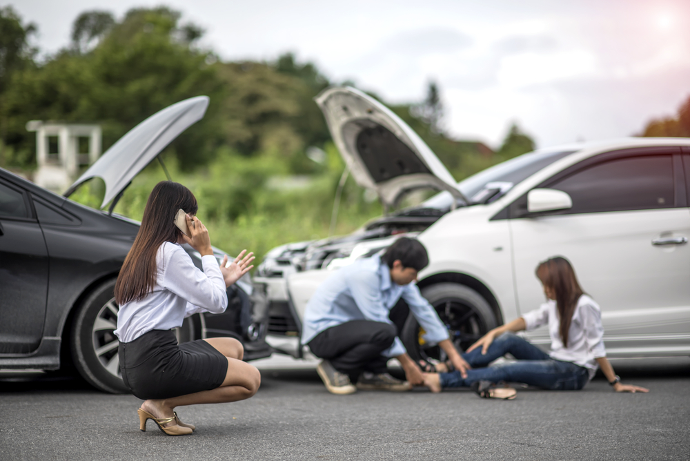 Policeman going over car accident scene Woman calling for help for injured woman after witnessing a car accident